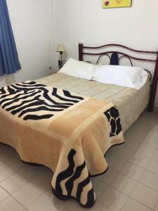 1 dormitorio con una manta de cebra en una cama en La Matilde en Villa Ciudad de América