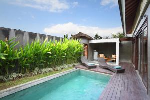 a swimming pool in a backyard with two chairs and a house at The Canggu Boutique Villas & Spa by ecommerceloka in Canggu