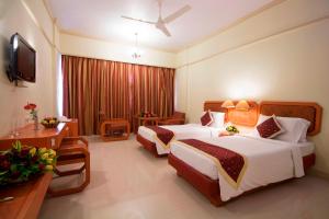 a hotel room with two beds and a television at Dolphin Hotel in Visakhapatnam