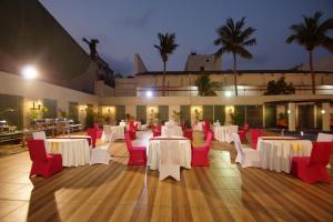 a banquet hall with white tables and red chairs at Dolphin Hotel in Visakhapatnam