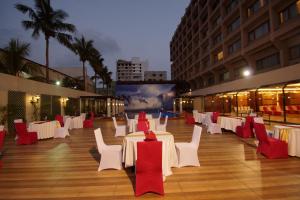 a banquet hall with white tables and red chairs at Dolphin Hotel in Visakhapatnam