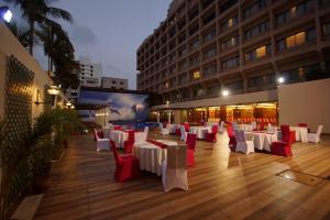 a restaurant with white and red tables and chairs at Dolphin Hotel in Visakhapatnam +37 photos