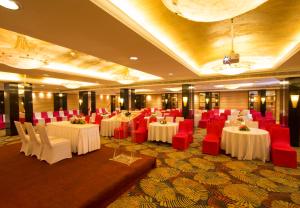 a banquet hall with white tables and red chairs at Dolphin Hotel in Visakhapatnam