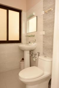 een witte badkamer met een toilet en een wastafel bij Hotel Mudita in Kathmandu