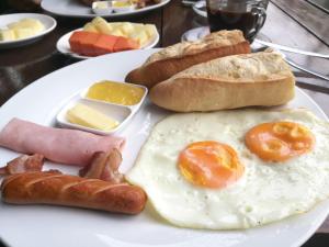 um prato de comida de pequeno-almoço com ovos, salsicha e pão em Ancient Luangprabang Hotel em Luang Prabang