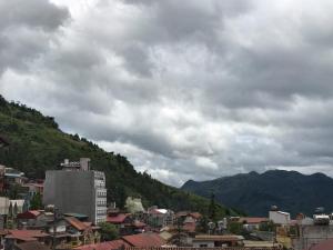 a city with buildings and mountains on a cloudy day at Camellia Guest House in Sapa
