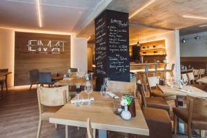 a restaurant with wooden tables and chairs and a chalkboard at HEIMAT | Hotel & Boarding House in Mainburg
