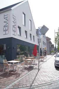 HEIMAT | Hotel & Boarding House في ماينبورغ: مجموعة طاولات وكراسي أمام المبنى