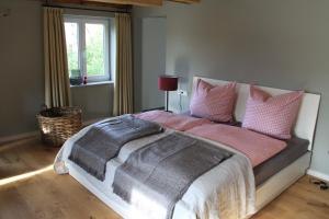 a bedroom with a large bed with pink and grey pillows at BB Baischhof Barabein in Warthausen