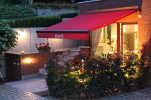 un restaurante con toldo rojo y algunas flores en B&B Au Roman Païs, en Braine-le-Château