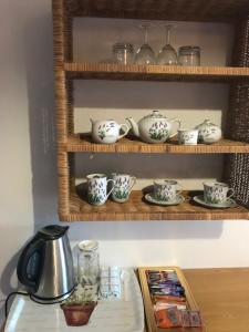 a shelf with tea pots and cups on it at Die Kersiehuis in Ficksburg