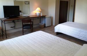 a bedroom with two beds and a desk with a television at Citystate Asturias Hotel Palawan in Puerto Princesa City