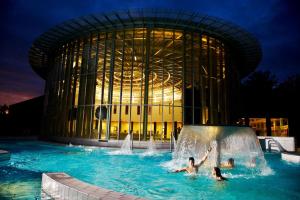 two people playing in a pool in front of a building at Les Lucioles in Francorchamps