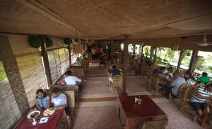 a group of people sitting at tables in a restaurant at Symphony Palms Beach Resort And Spa in Havelock Island