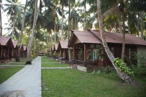 a house with trees and palm trees at Symphony Palms Beach Resort And Spa in Havelock Island