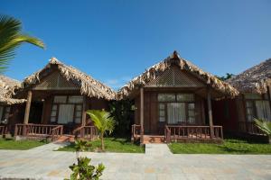 a row of cottages with thatched roofs at Symphony Palms Beach Resort And Spa in Havelock Island