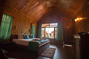 a bedroom with a bed with wooden walls and a window at Symphony Palms Beach Resort And Spa in Havelock Island