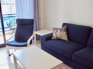 ein Wohnzimmer mit einem blauen Sofa und 2 Stühlen in der Unterkunft Apartamento Victor in Tossa de Mar