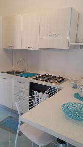 a white kitchen with a stove and a table at Acquamarina Accommodation in Massa Lubrense