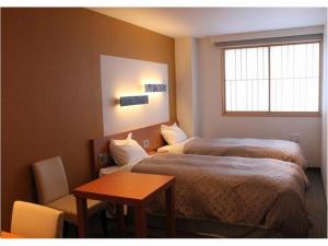 una camera d'albergo con due letti, un tavolo e una finestra di Hotel Winery Hill a Izu