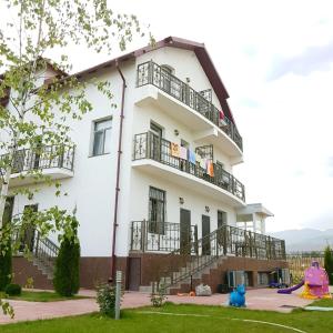 a white building with balconies and a blue teddy bear at Guest house Ak Keme in Bosteri
