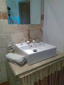 a white sink with a mirror on top of a counter at Maison de Campagne in Sarragia