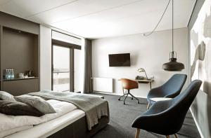 a bedroom with a bed and two chairs and a desk at Comwell Roskilde in Roskilde
