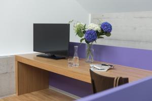 un escritorio con TV y un jarrón de flores en Barracuda, en Lenzburg