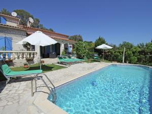 a swimming pool with chairs and an umbrella at Beautiful holiday home with private pool in Bagnols-en-Forêt