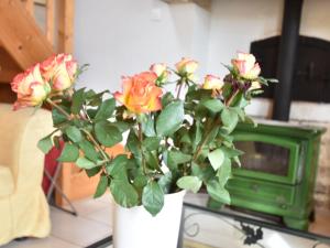 een vaas met rozen op een tafel naast een tv bij Cozy Cottage in Fresville with Garden in Fresville