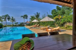 a dining table and chairs next to a swimming pool at Villa Nirwana in Lovina