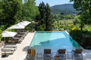 a swimming pool with lounge chairs and umbrellas at Les Lodges Sainte-Victoire Hotel & Spa in Aix-en-Provence