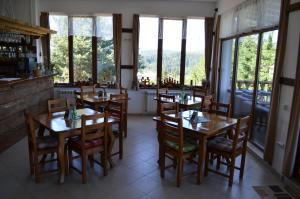 a restaurant with wooden tables and chairs and windows at EldoSport Hotel in Dospat