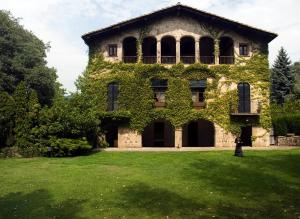 un bâtiment recouvert de lierre sur une pelouse dans l'établissement Les Cols Pavellons, à Olot