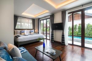 a bedroom with a bed and a couch and a tv at NH Collection Samui Peace Resort in Bophut