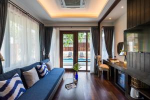 a living room with a blue couch and a large window at NH Collection Samui Peace Resort in Bophut