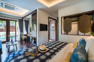 a bedroom with a large bed and a living room at NH Collection Samui Peace Resort in Bophut