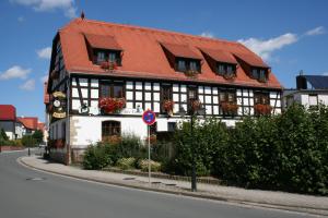 a black and white building with a red roof at Gasthaus & Hotel Zur Linde in Hermsdorf