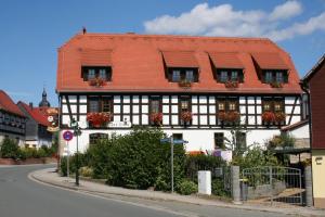 a black and white building with flowers on the windows at Gasthaus & Hotel Zur Linde in Hermsdorf