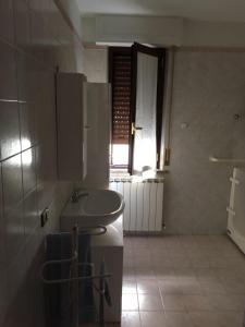 baño blanco con lavabo y ventana en Appartamento Biancospino, en Gualdo Tadino