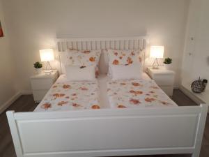 a bedroom with a white bed with two lamps at Ferienwohnung Weitblick in Wolfshagen