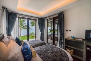 a bedroom with a bed and a tv and a window at NH Collection Samui Peace Resort in Bophut