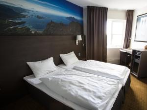 una camera da letto con un grande letto con lenzuola e cuscini bianchi di Thon PartnerHotel Skagen a Bodø