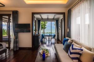 a living room with a couch and a view of the ocean at NH Collection Samui Peace Resort in Bophut