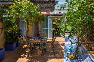 un patio con mesa, sillas y árboles en Dimora Dei Giganti, en Nápoles