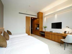 a bedroom with a white bed and a flat screen tv at Hotel COZi Wetland in Hong Kong