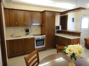 una cocina con armarios de madera y un jarrón de flores sobre una mesa en Perdika Suites, en Perdika