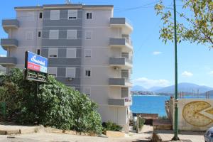a tall building with a sign in front of it at Port Side Sarande in Sarandë
