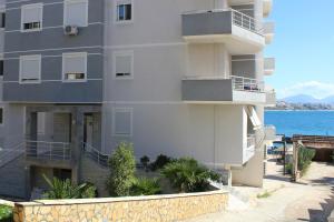 a large white building with a balcony next to the water at Port Side Sarande in Sarandë
