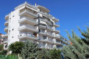 a white apartment building with trees in front of it at Port Side Sarande in Sarandë